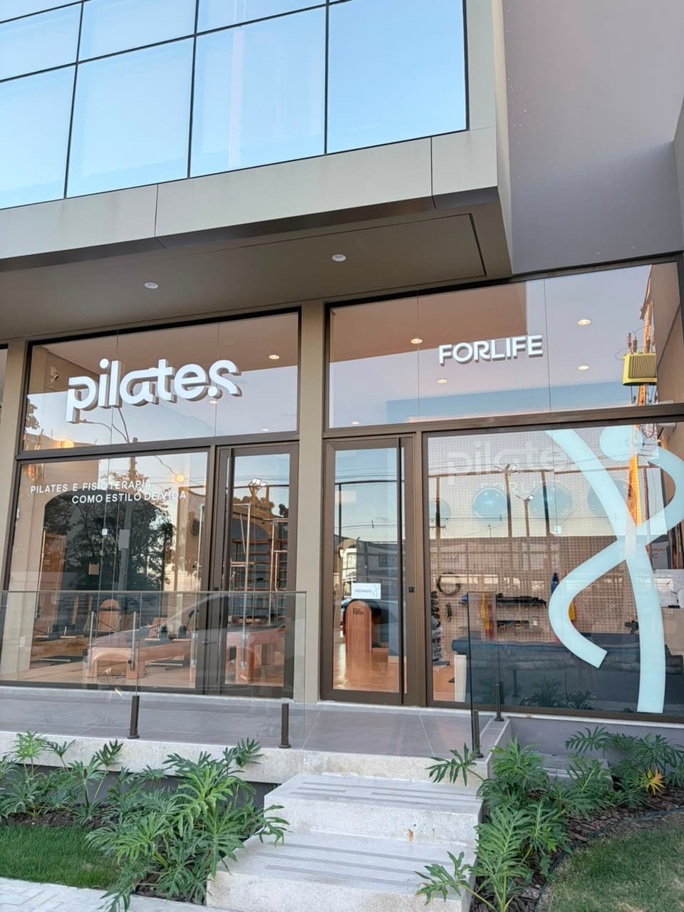 Fachada do estúdio Pilates ForLife, com letreiro iluminado e fachada de vidro